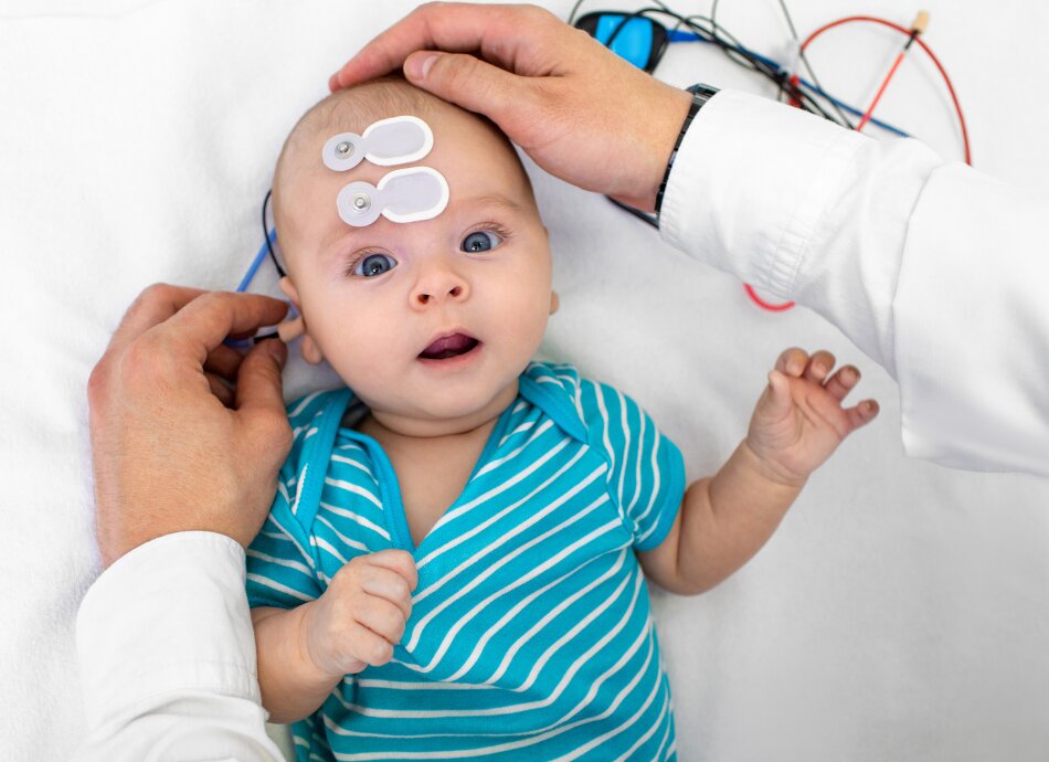 Baby lying on white sheet gets hearing test