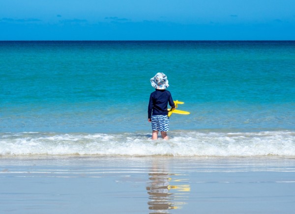 Child in hat and protective clothing at the beach