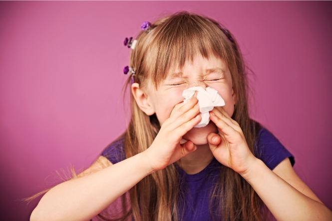 Girl blowing her nose into tissue 