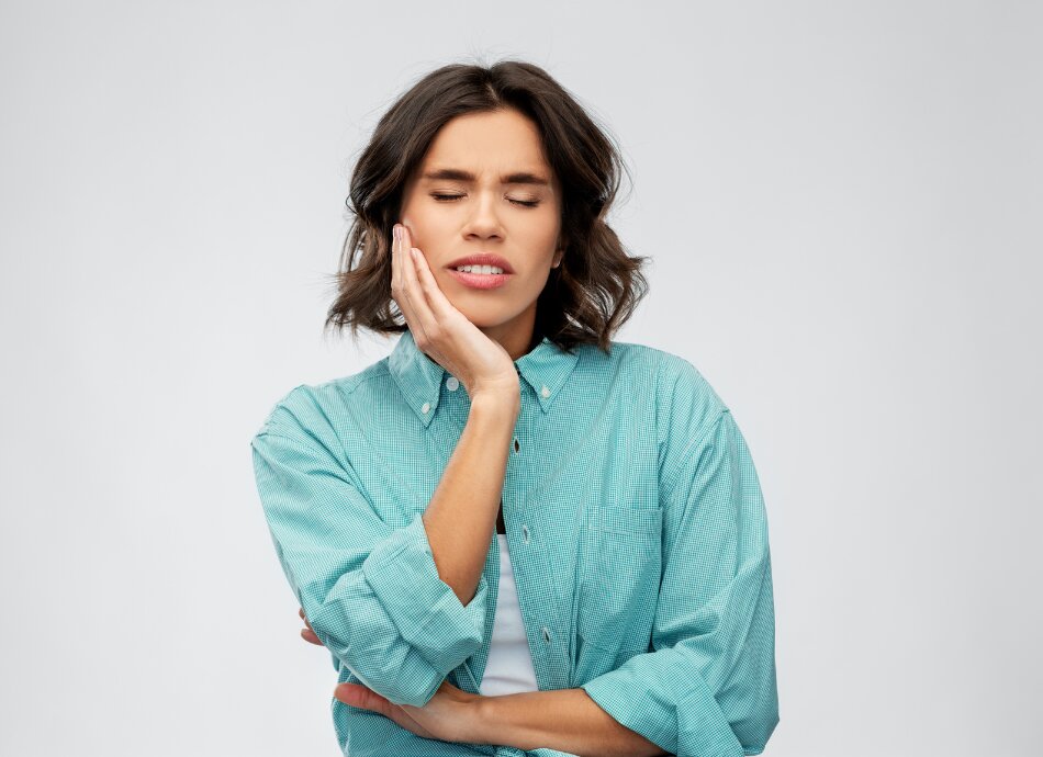 Woman holding jaw in pain with eyes shut 