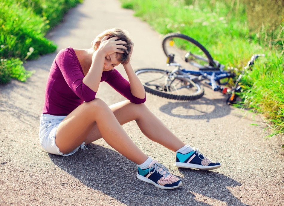 Woman sits outside with head injury having fallen off bike